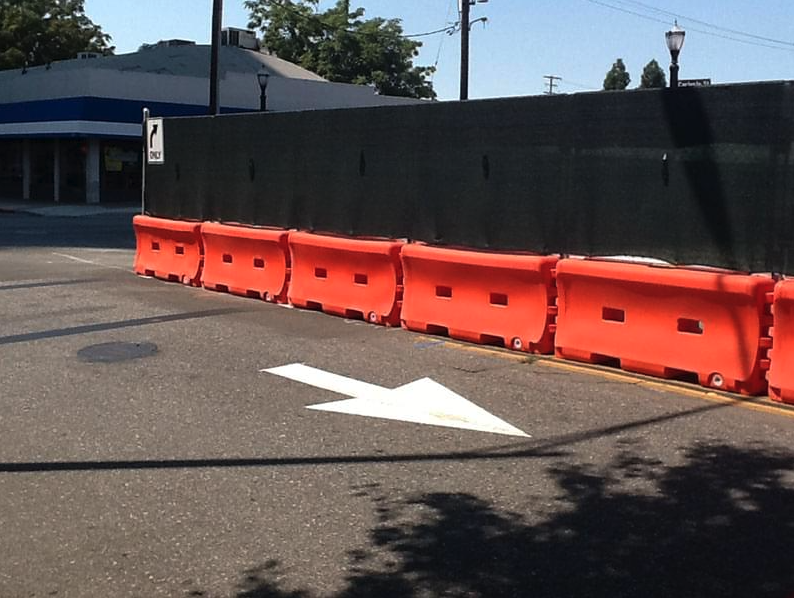 Orange plastic water wall safety barriers used to block part of the street for traffic safety in Northern California