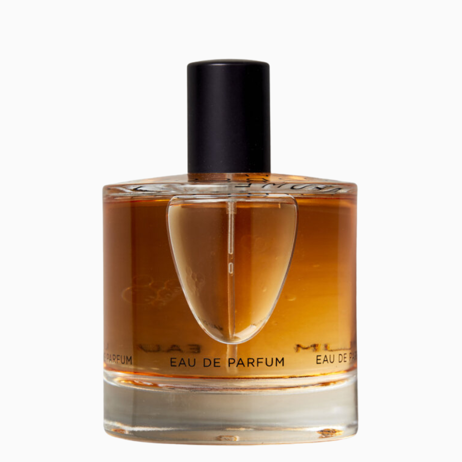 A bottle of Eau de Parfum perfume with a black cap, transparent glass, and amber-colored liquid inside.