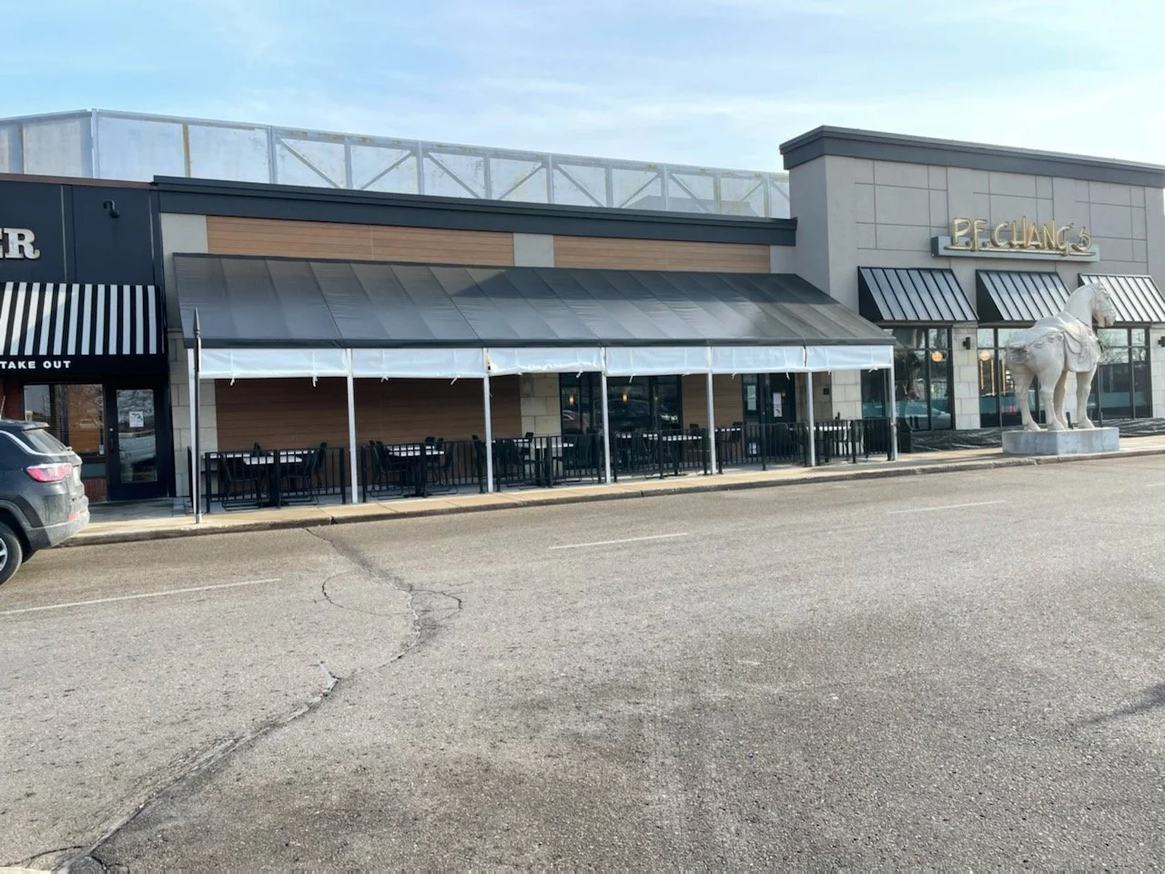 Exterior view of a restaurant with outdoor seating and a large horse statue.