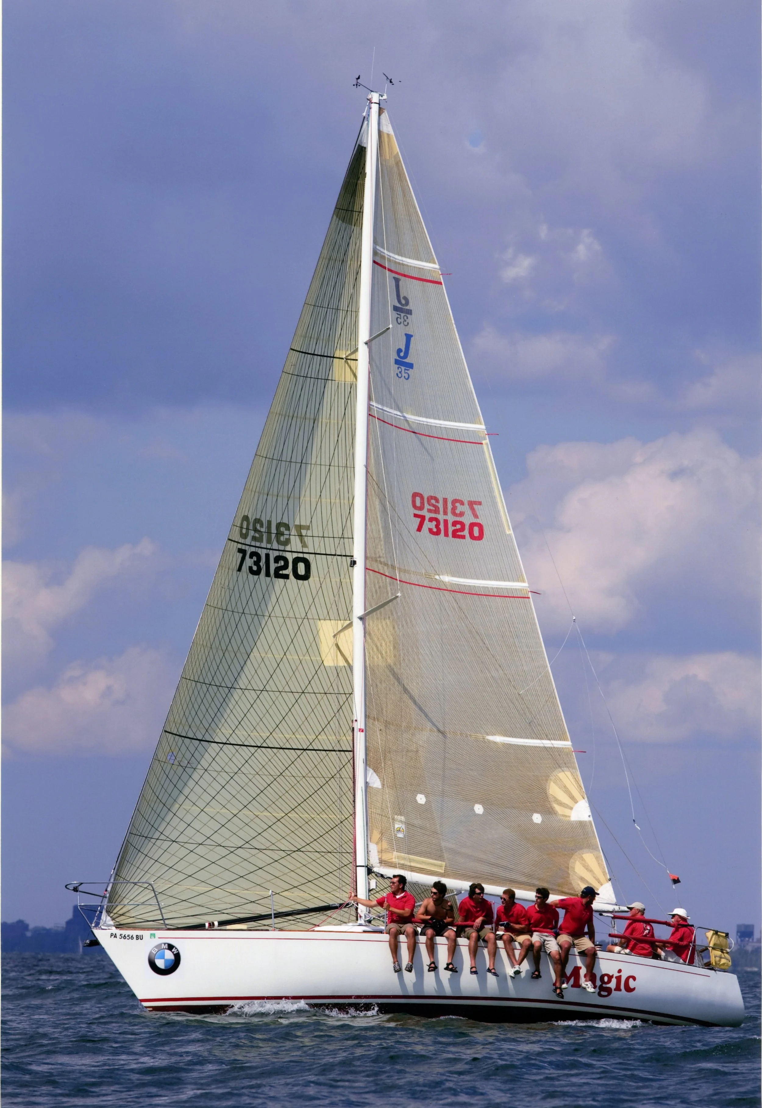 Sailing yacht with crew in red shirts on open water