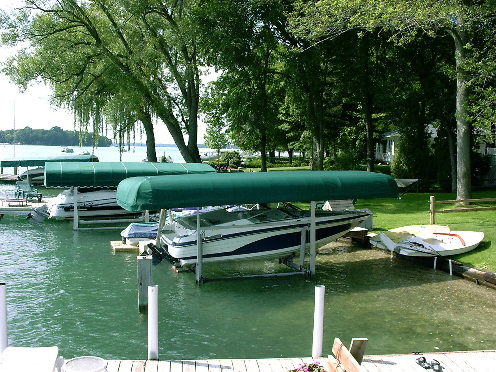 Boat dock with motorboats and covers on a lake surrounded by trees