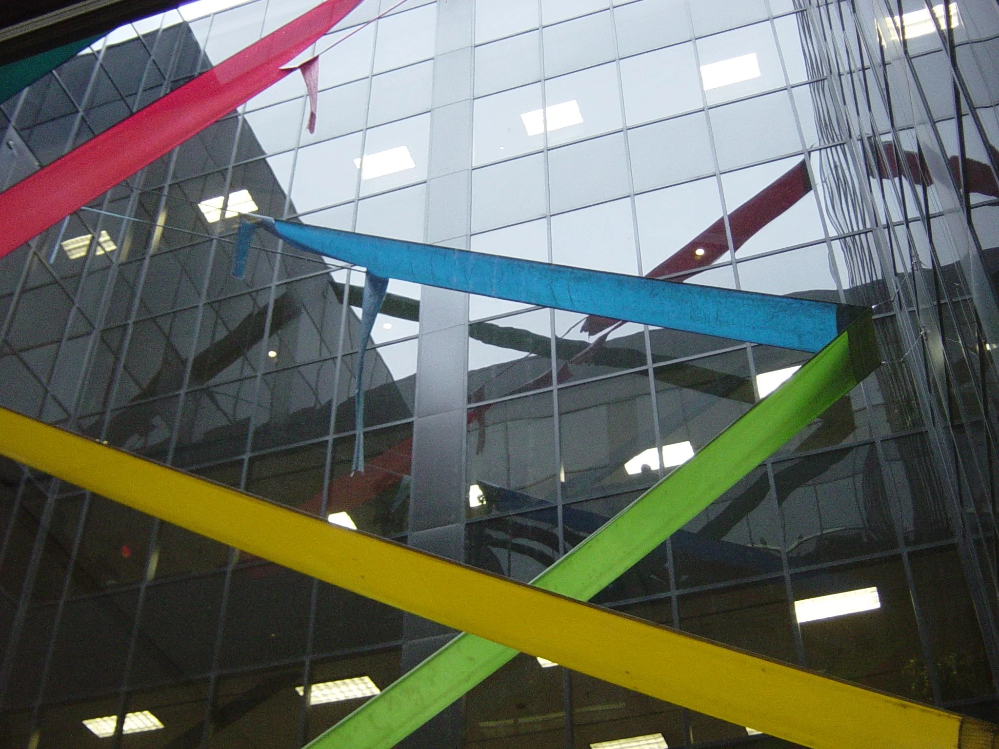 Colorful ribbons hanging in front of a glass building.