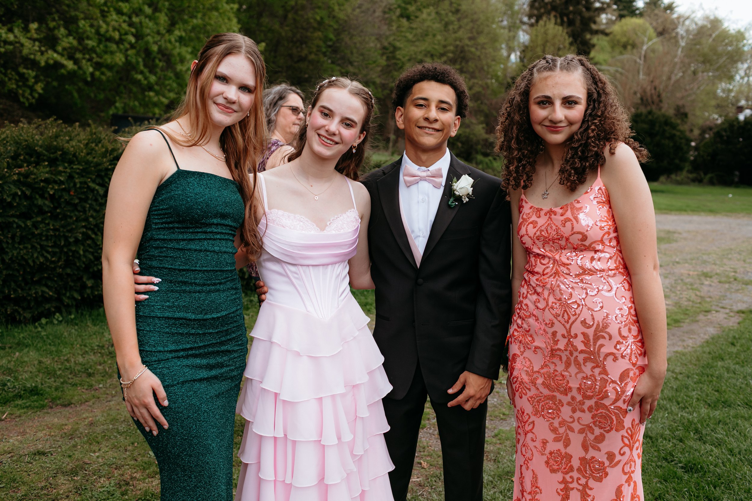 Group of young people in formal attire, outdoors at a dance or prom event.