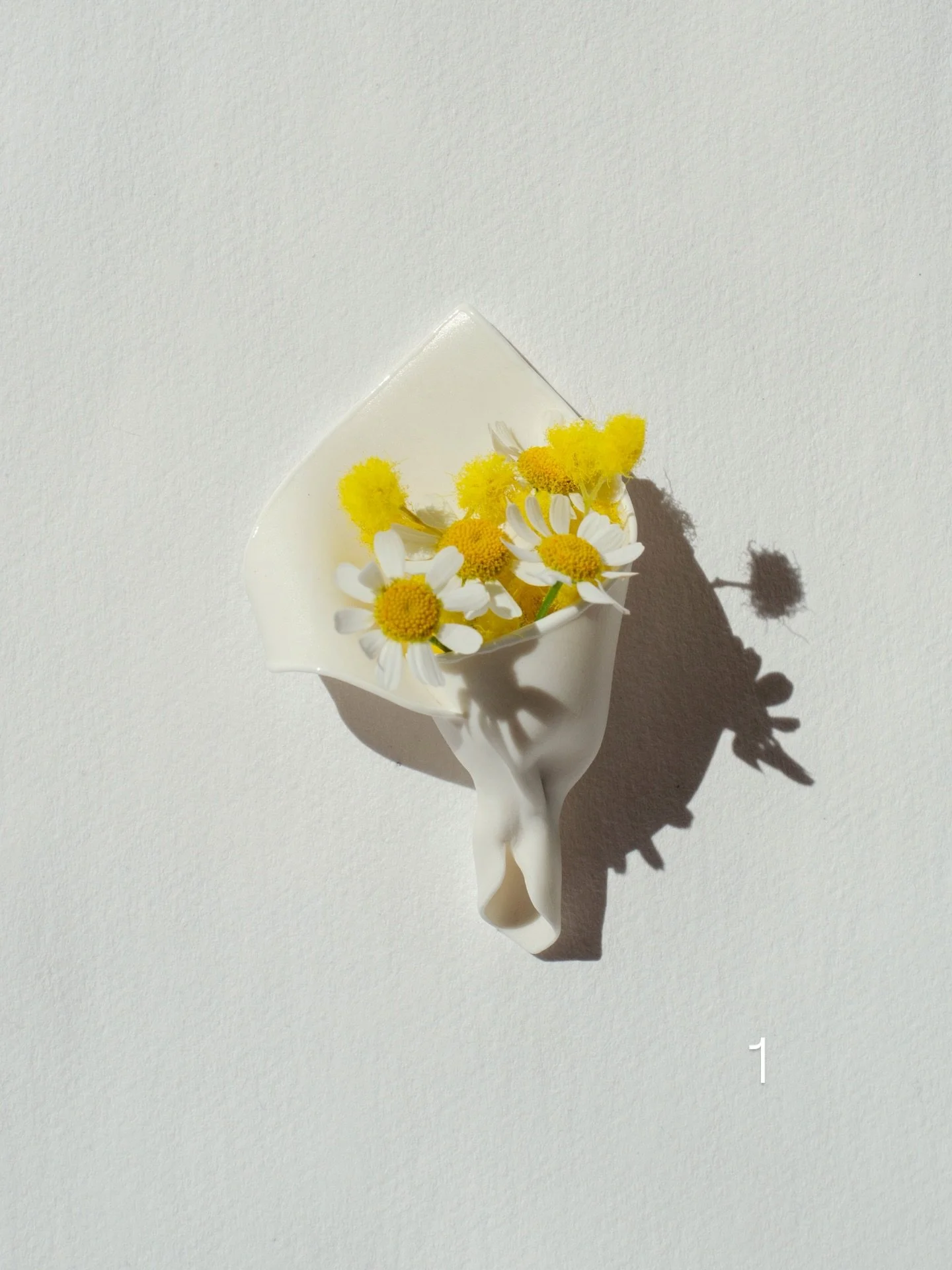 Inspired by the simple gesture of picking a bloom along the way, these porcelain brooches imitate a small bouquet wrap &mdash; one you can pin on and fill with a flower.

Here are 12 different models, each unique, priced at &euro;35.
Sizes range from