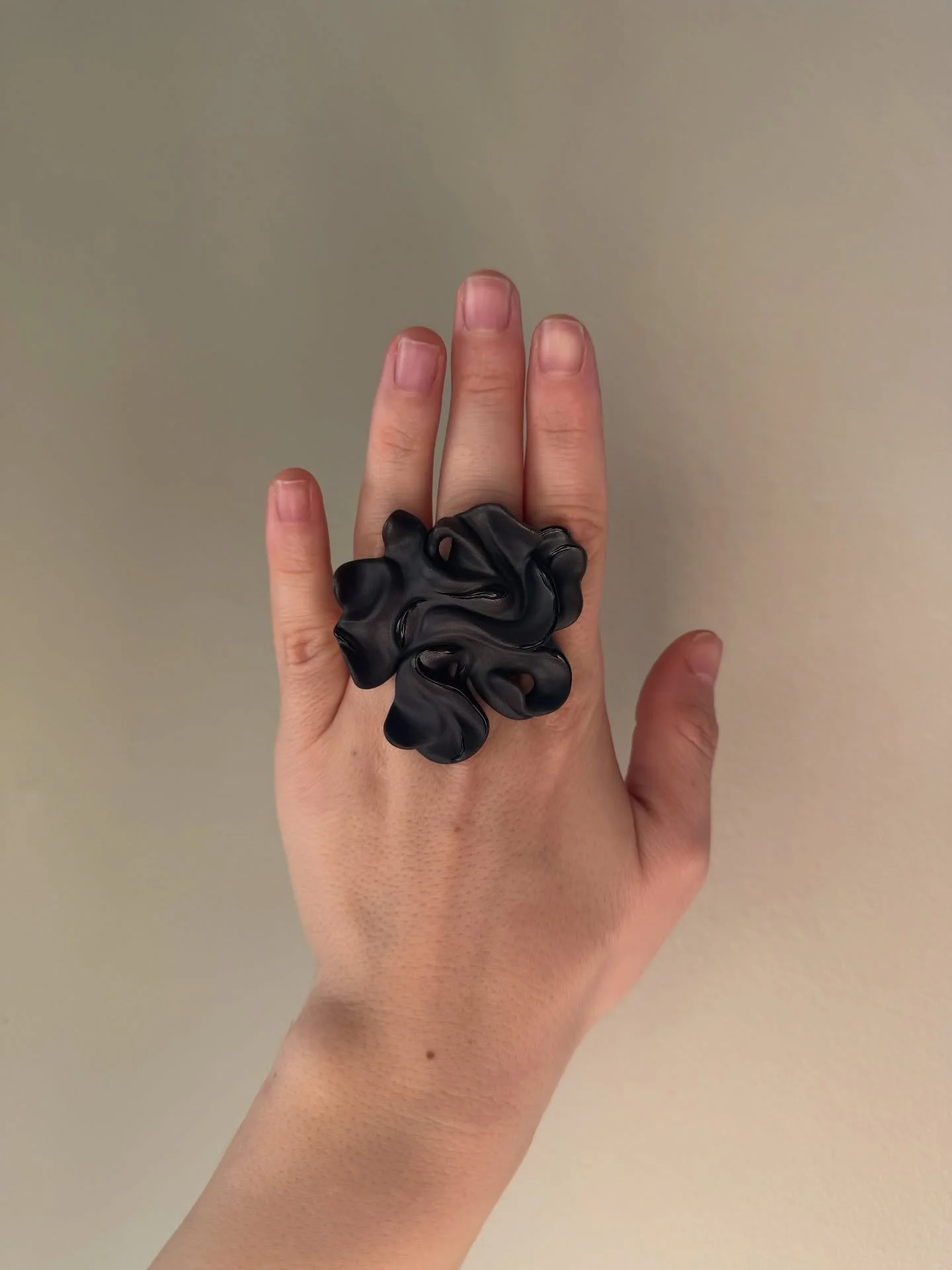 Sculptural black porcelain ring. 
It has an inner diameter of 18.2 mm, corresponding to a European ring size 57. The price is &euro;150.
A matte surface with subtle glossy accents.
Completely handmade, with visible traces of the making process.