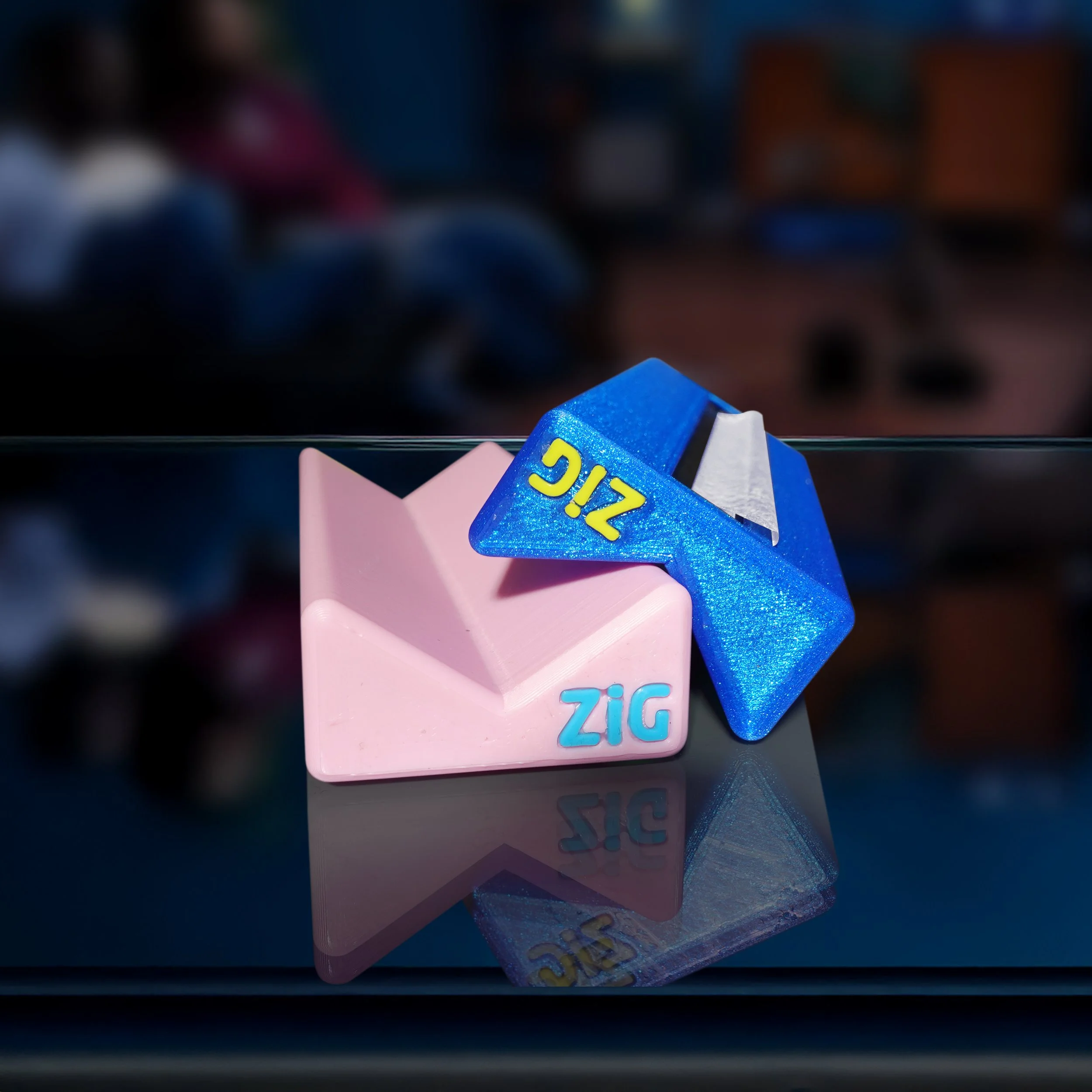 A pink and a blue Z ZigaJig King Slim Rolling Racks placed on a reflective surface.