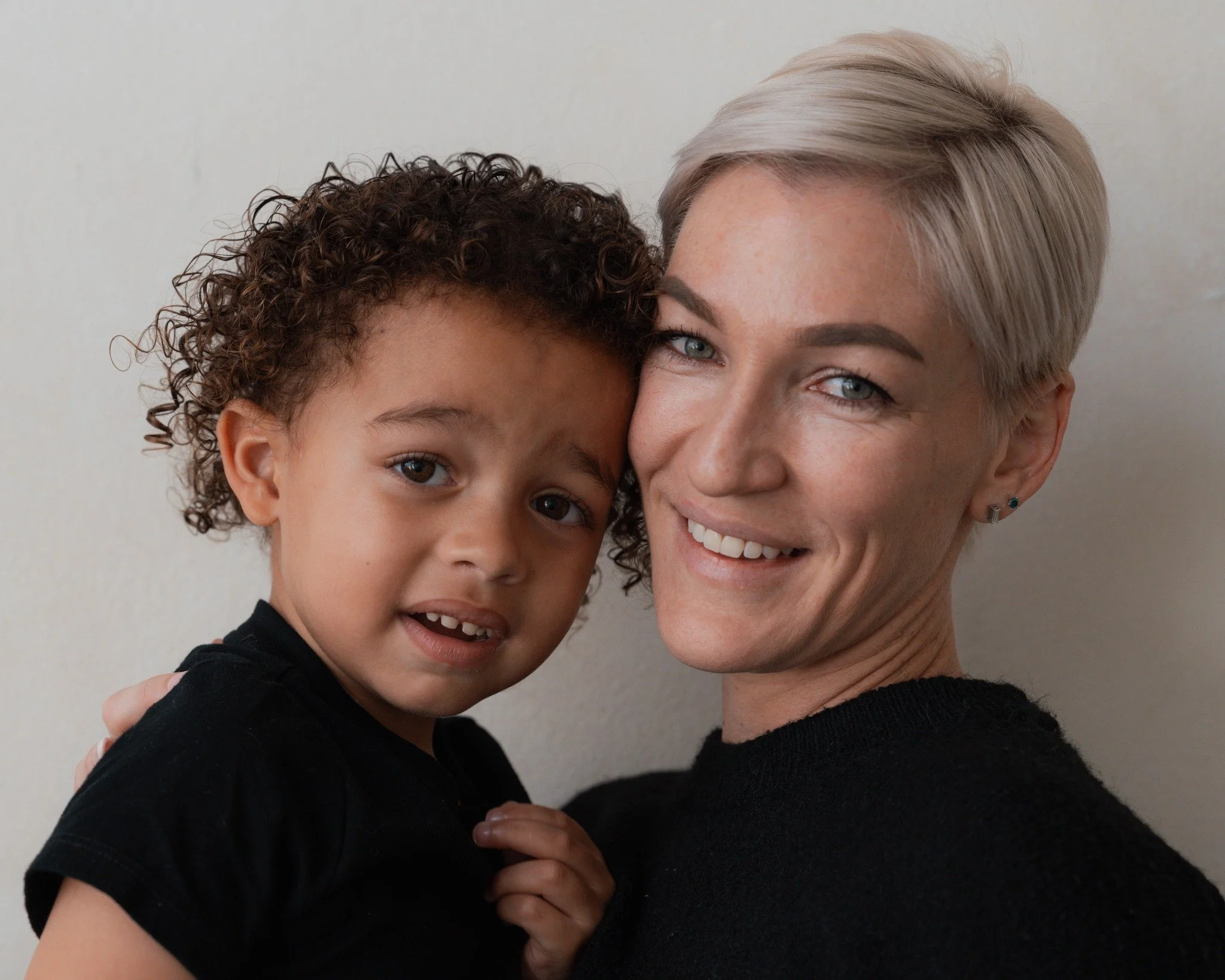 A mother and young son smiling together in a close-up portrait