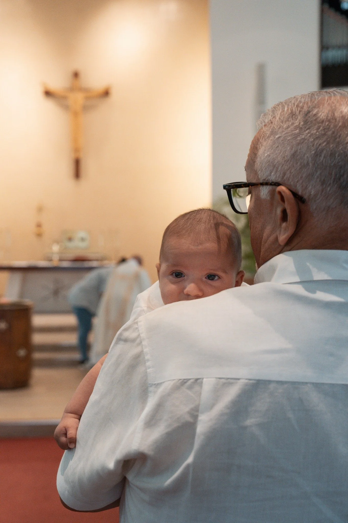 Baby looking over a man’s shoulder inside a church