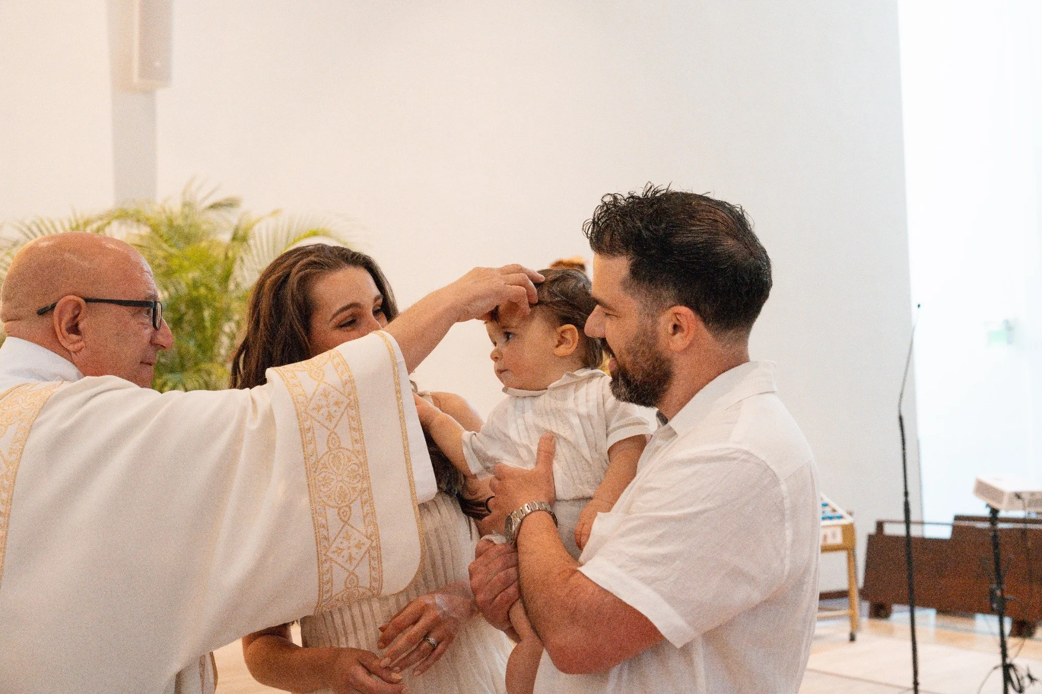 Priest blessing a child held by family during a baptism ceremony