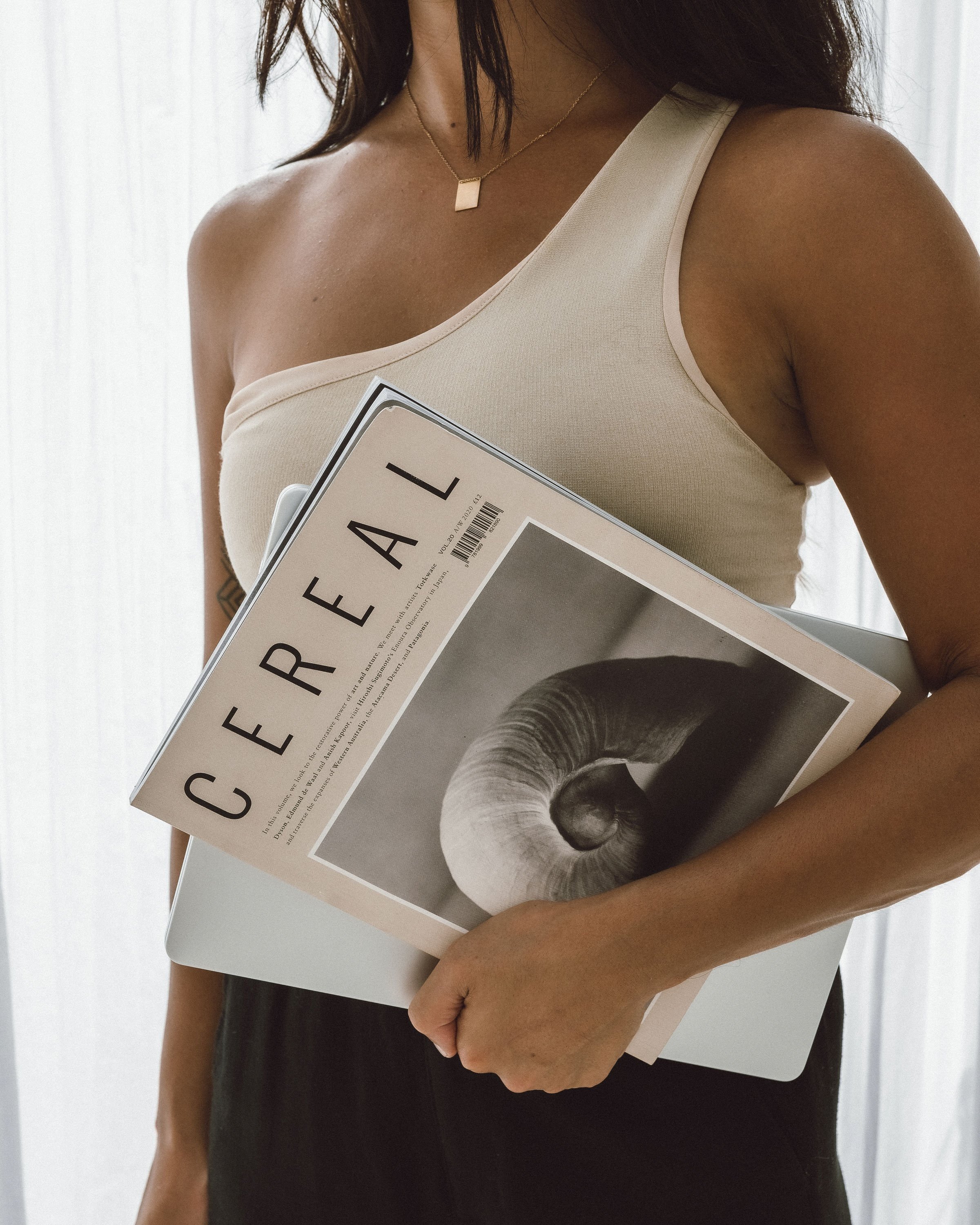 Person holding a Cereal magazine and a laptop