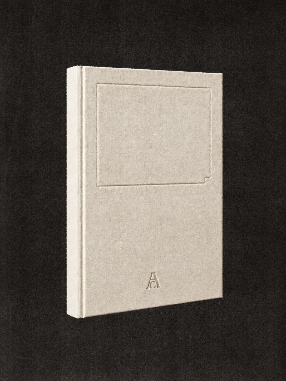 A white hardcover book has a minimalist design with a square embossed on the front cover and a small letter 'A' embossed near the bottom.