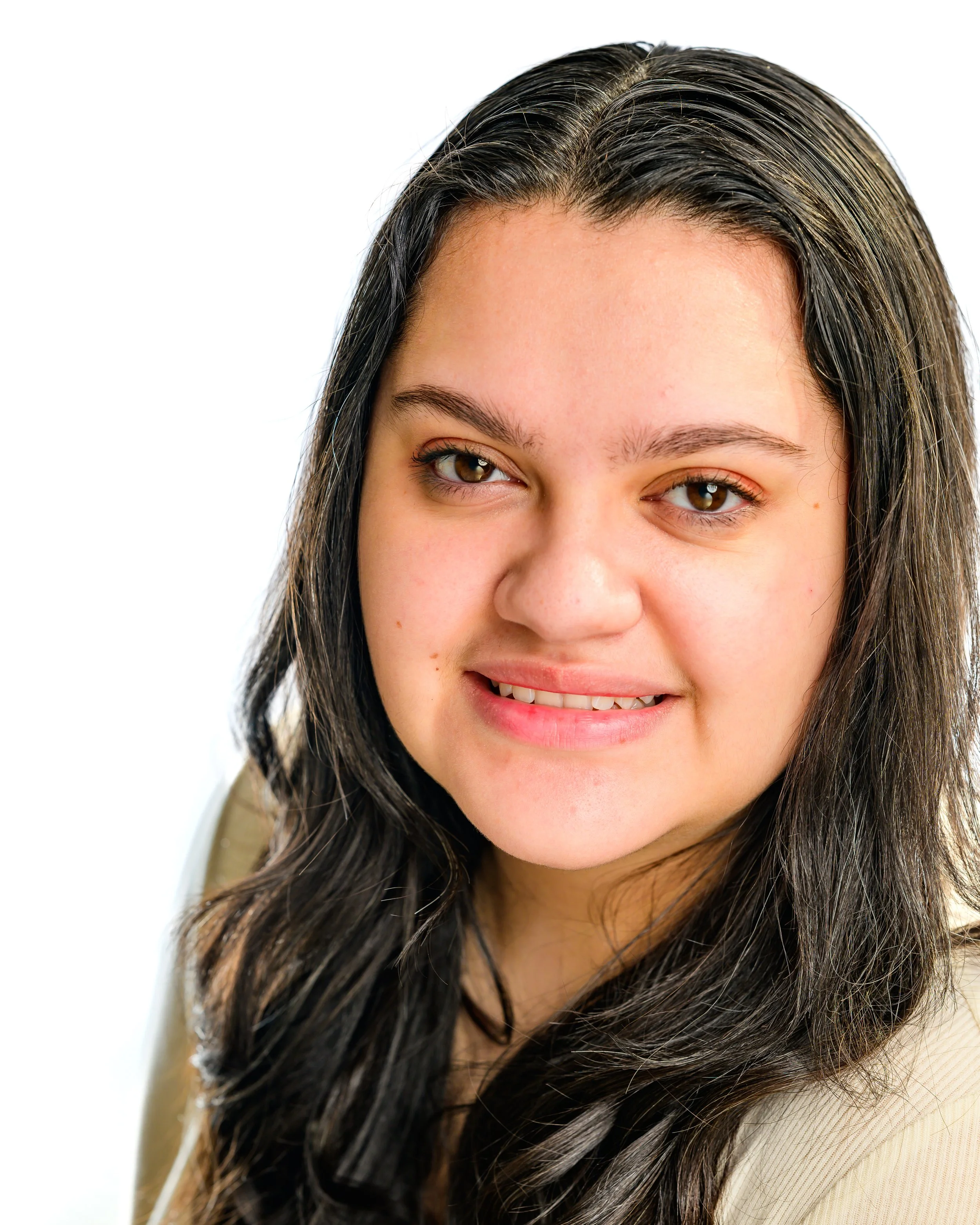 Smiling person with long dark hair and a light-colored top, on a white background.