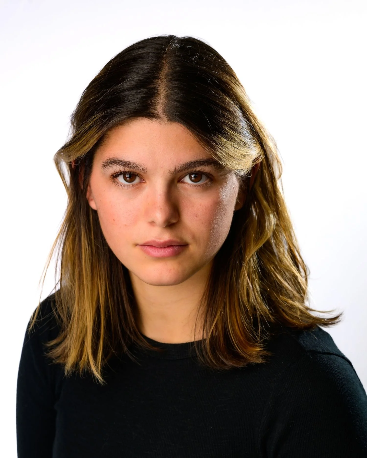 Portrait of a young person with medium-length brown hair wearing a black shirt against a plain white background.