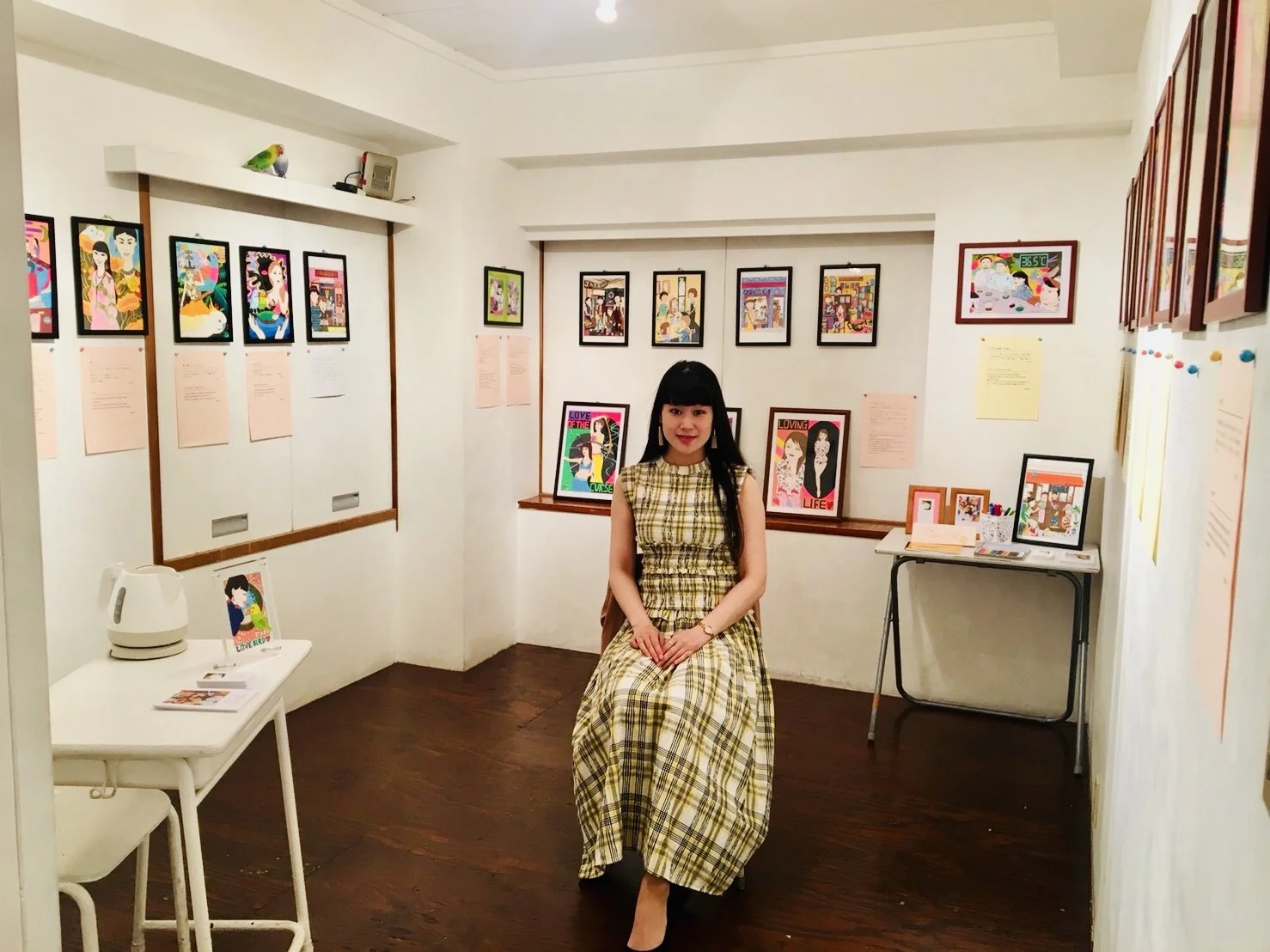 ギャラリー内に座っている女性と壁に掛けられたアート作品。