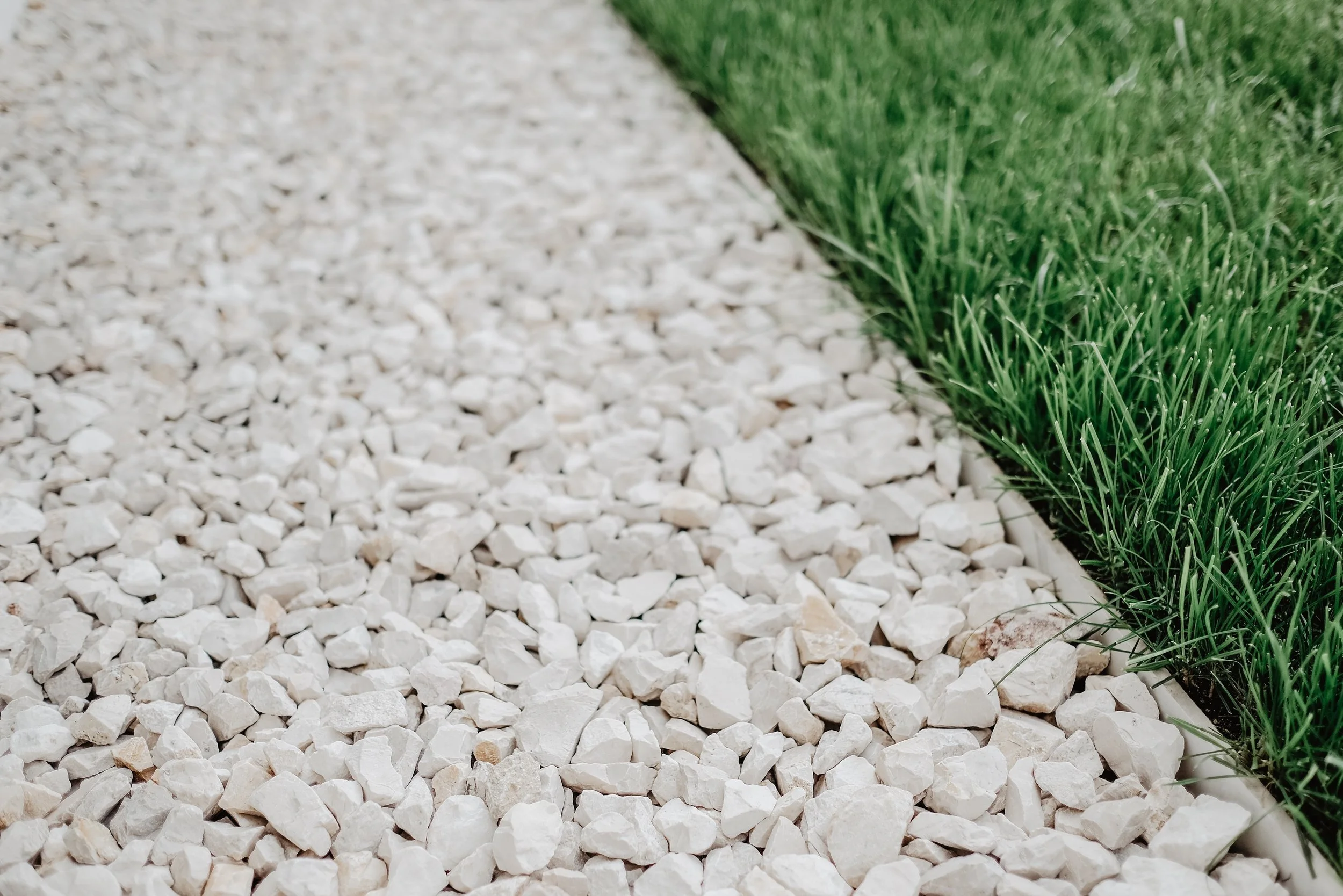 Close-up view of a gravel path next to a strip of green grass.