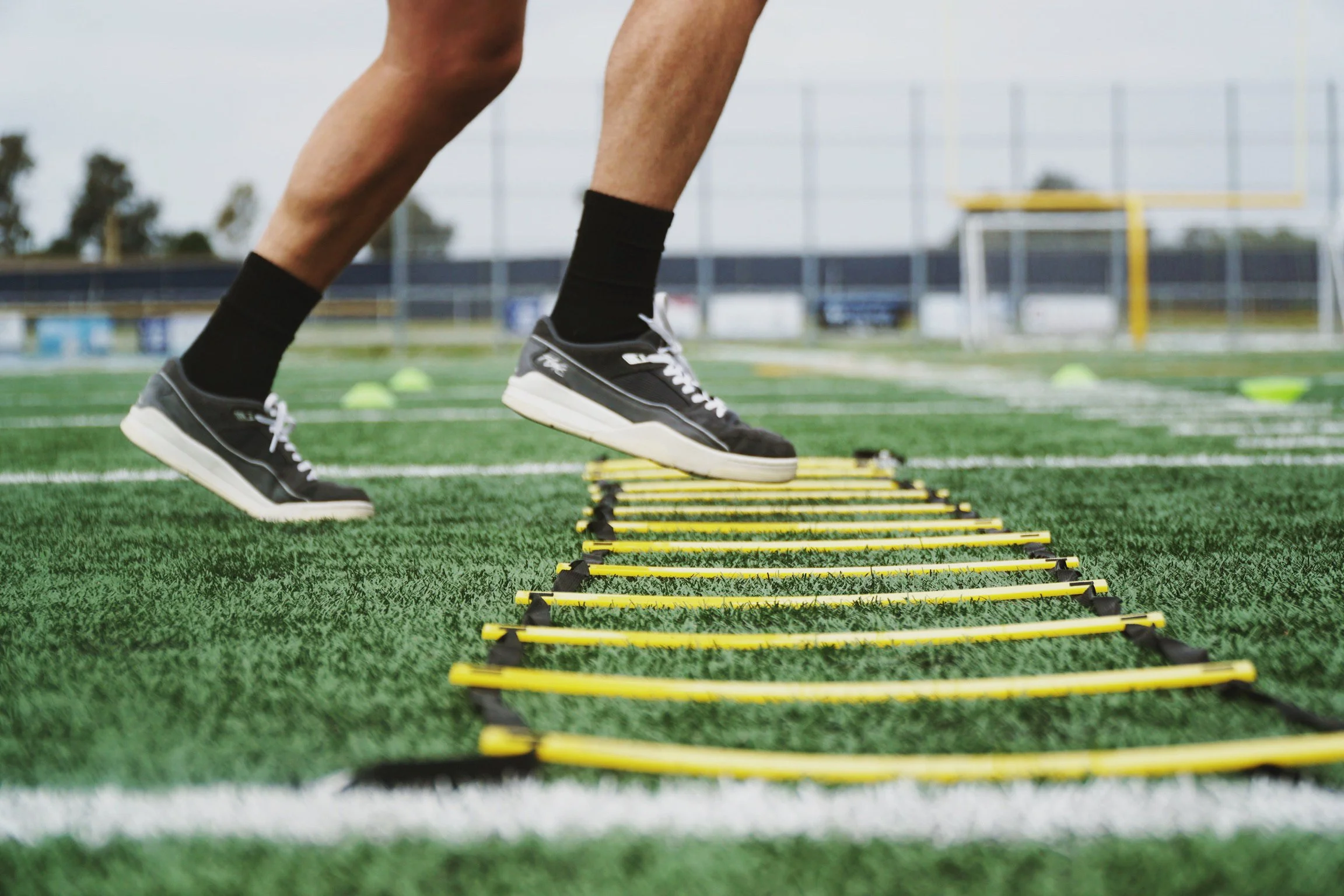 Person performing agility ladder drills on grass field
