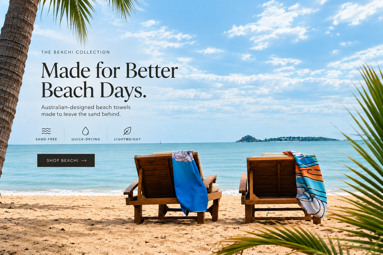 Two wooden beach chairs with colorful BEACHI beach towels sitting on sand by the ocean, with a blue sky and small island in the background, promoting Australian-designed BEACHI beach towels.