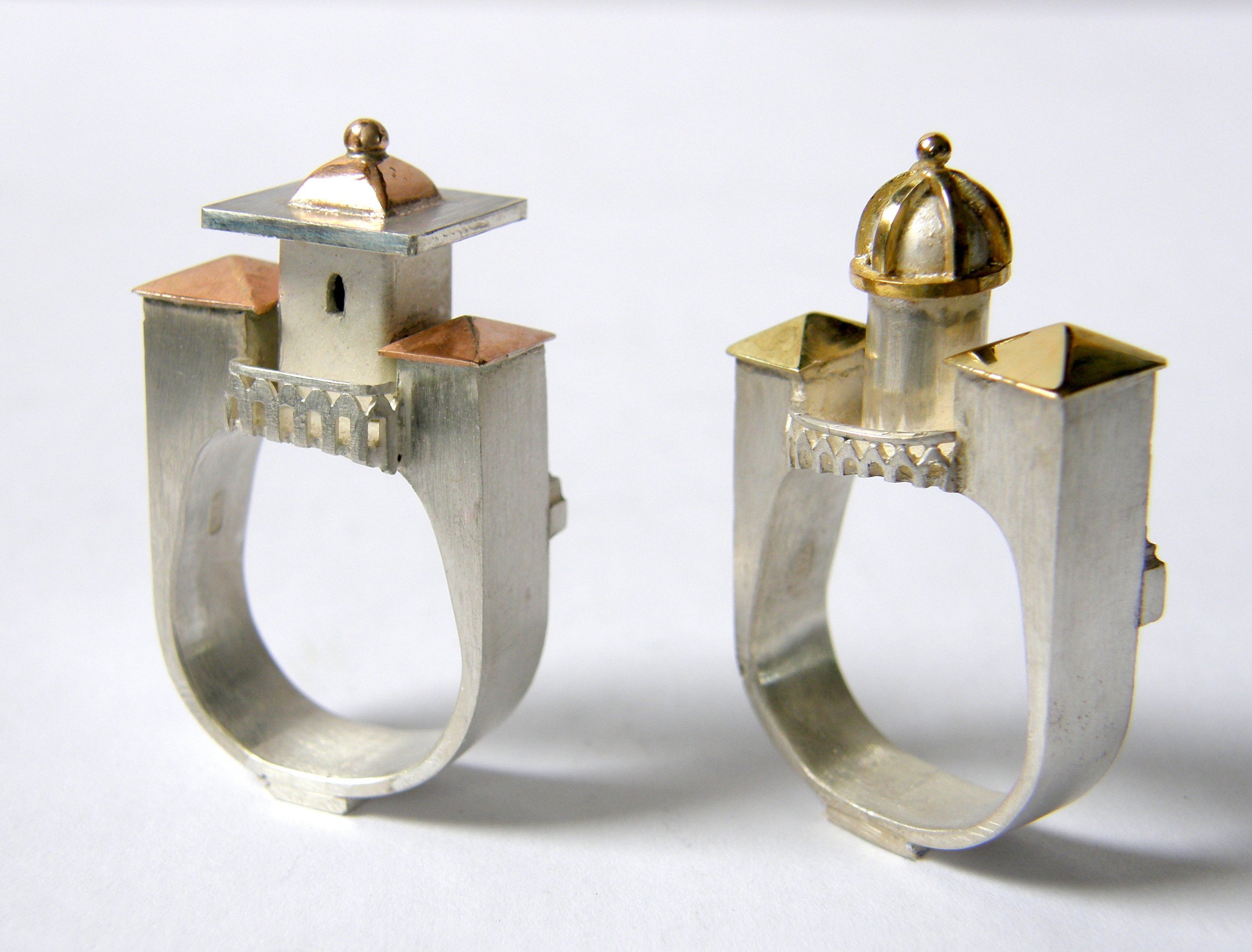 A person in a blue work uniform using a hammer to forge or shape a large metal pipe or tube.