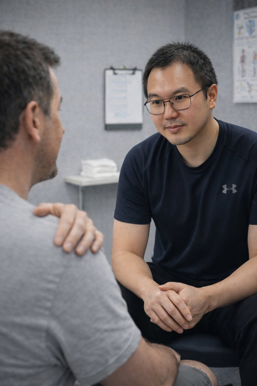 Sam listens to a male patient during a counseling session, sitting in a clinical office.