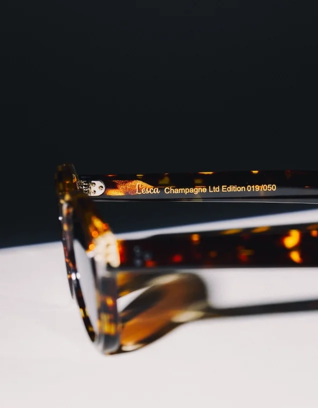 Detailní pohled na vnitřní stranu transparentní želvovinové straničky brýlí s vyrytým zlatým nápisem Lesca Champagne Ltd Edition a pořadovým číslem 019/050.