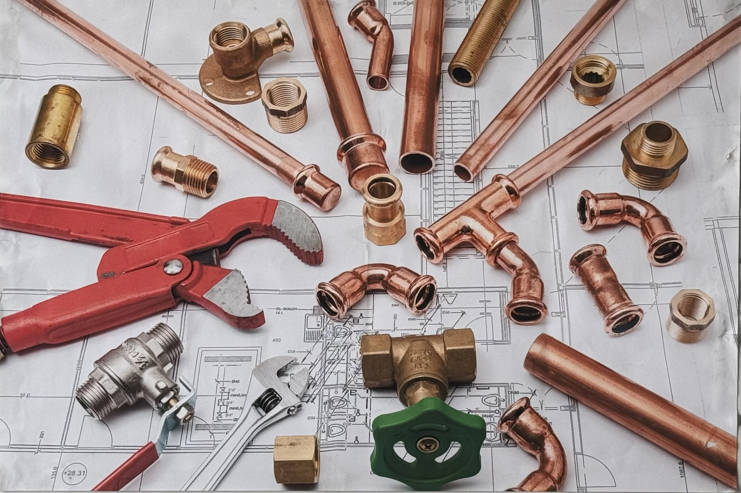 Copper plumbing pipes, fittings, and tools on a technical blueprint.