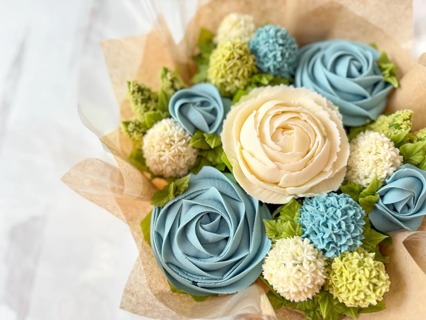 Soft blues, creamy ivory, and fresh spring greens 🤍🌿

This seven-cupcake bouquet is giving cool mornings, budding gardens, and that first breath of spring air. Featuring swirl blue roses, fluffy hydrangea clusters, and a buttery ivory peony center 