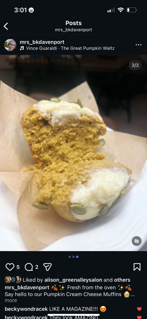 Pumpkin muffin with cream cheese frosting, topped with green pumpkin seeds, on parchment paper.