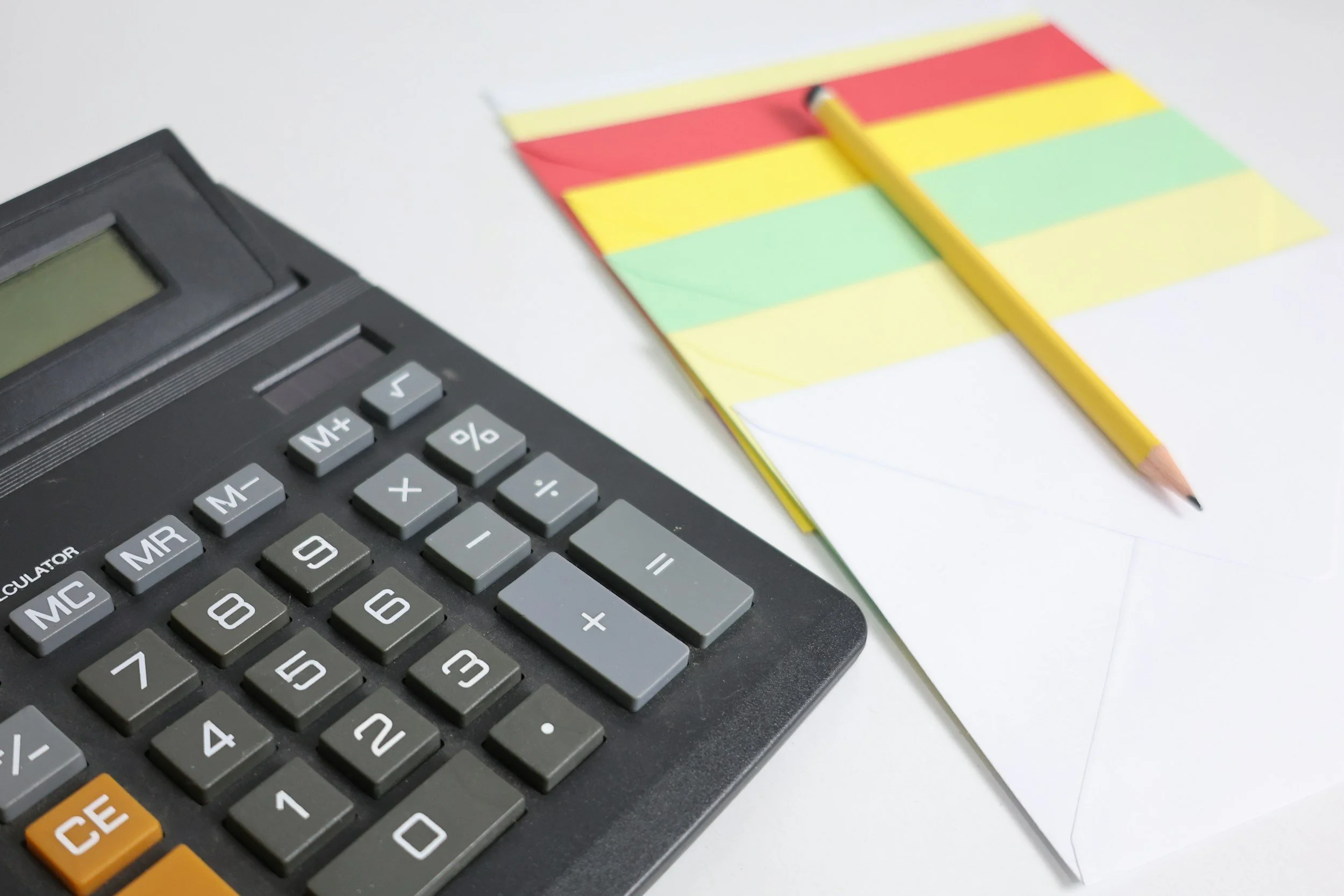 Calculator and colorful index cards with a yellow pencil on a white surface.