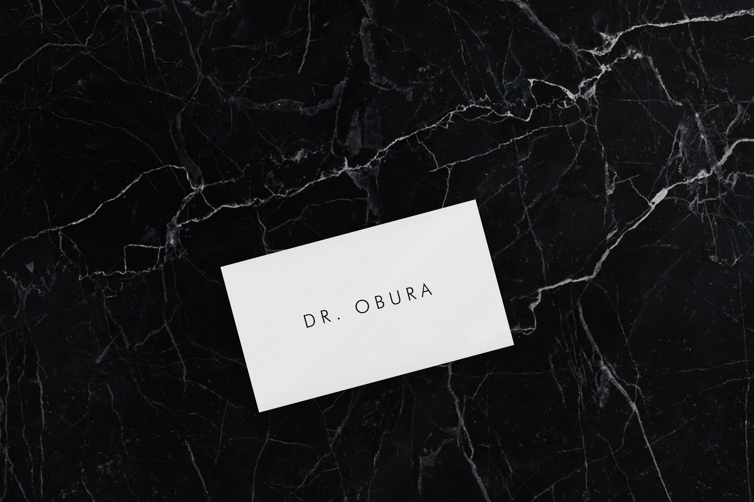 Minimalist business card featuring the clinic's wordmark, printed on textured premium stock for in-clinic use.