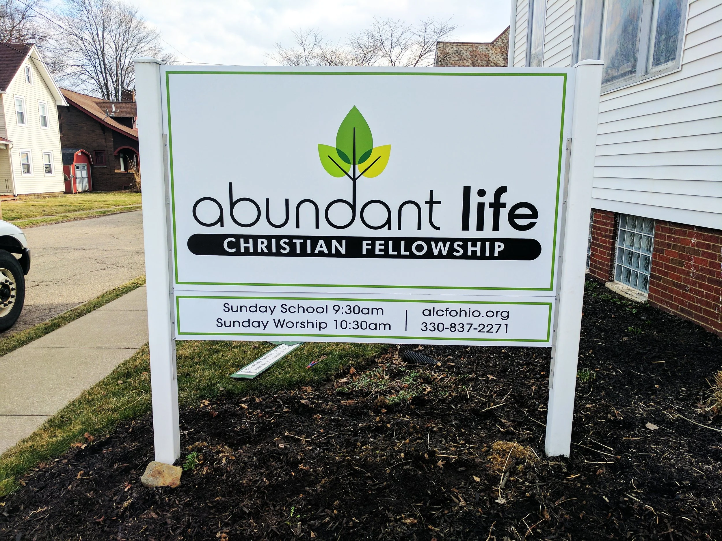 Sign for Abundant Life Christian Fellowship with service times and contact information.