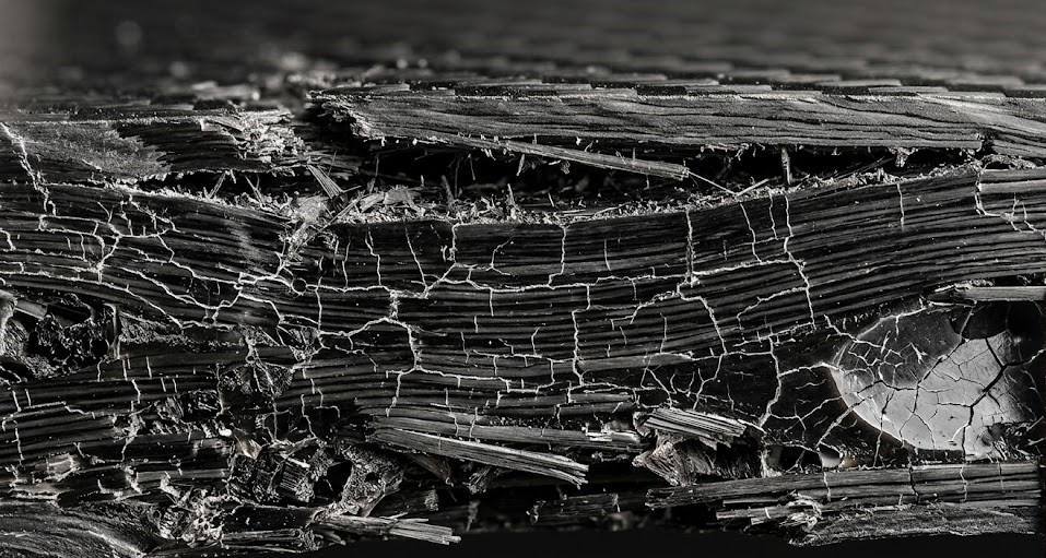 A micro view of composite failure, demonstrating the breakdown of polymer resin and subsequent carbon fiber separation.