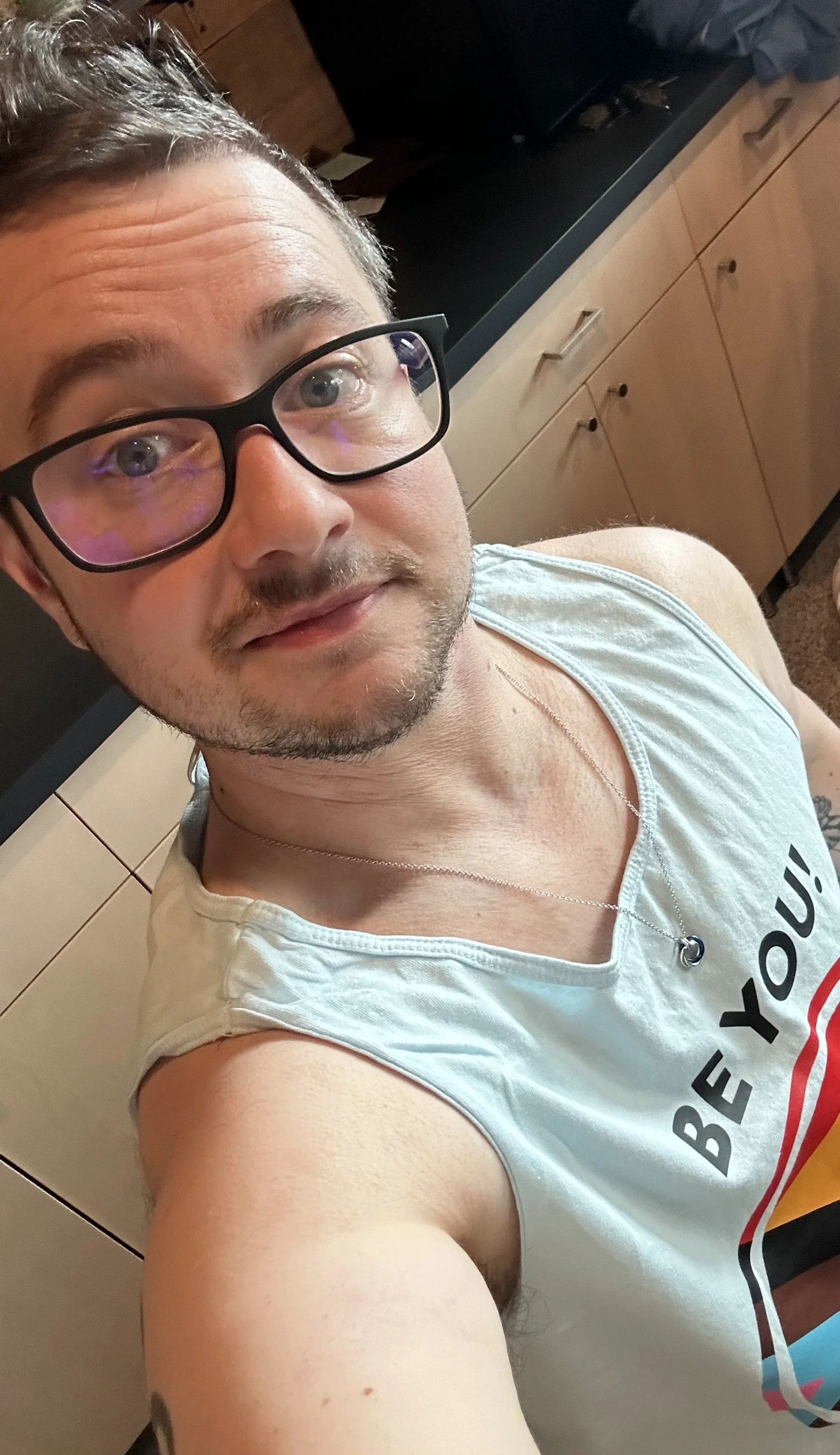 Selfie of a man wearing glasses and a tank top with the phrase "BE YOU!"