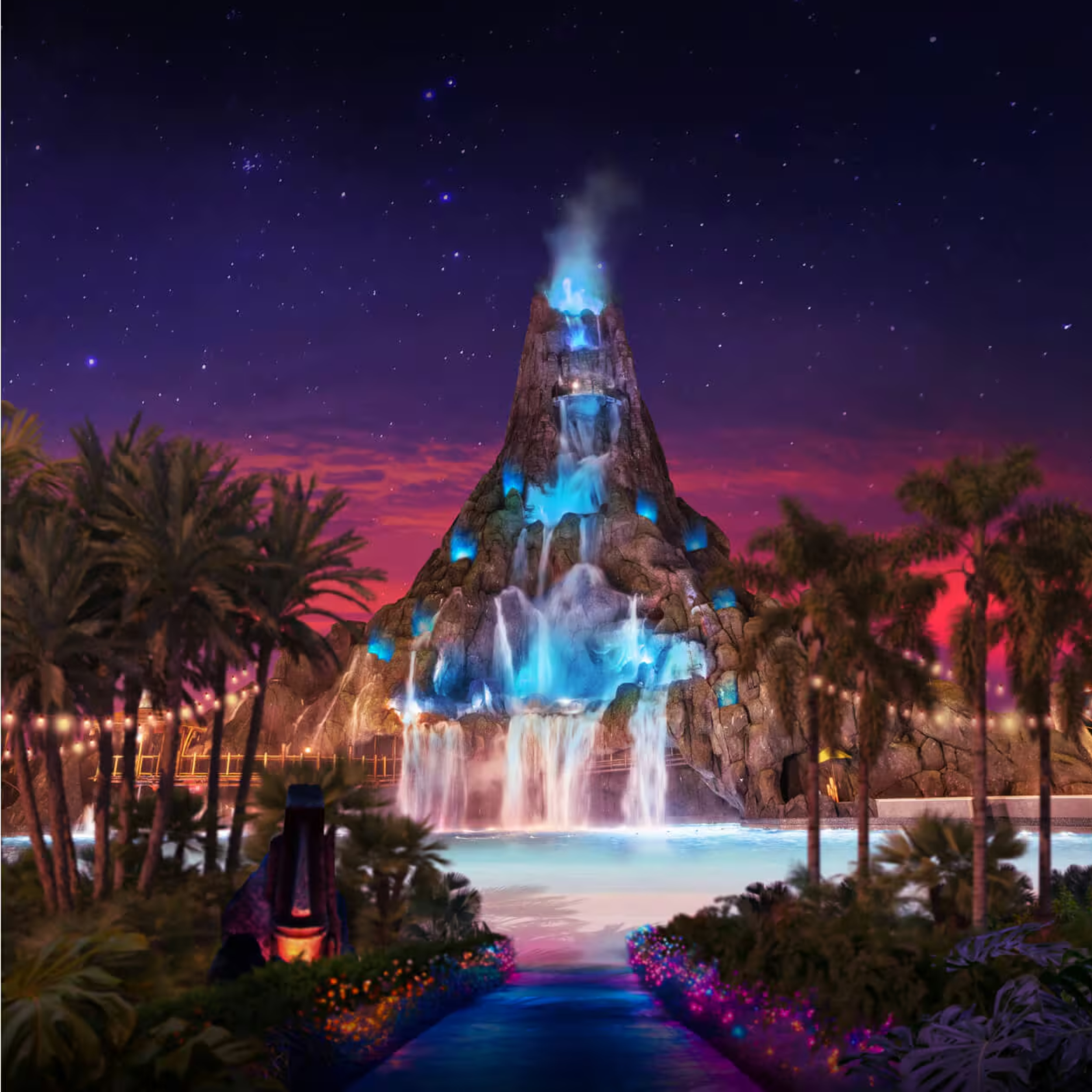 Nighttime view of a themed volcano water attraction with waterfalls and blue lighting, surrounded by palm trees and colorful lights, under a starry sky with pink and purple clouds.