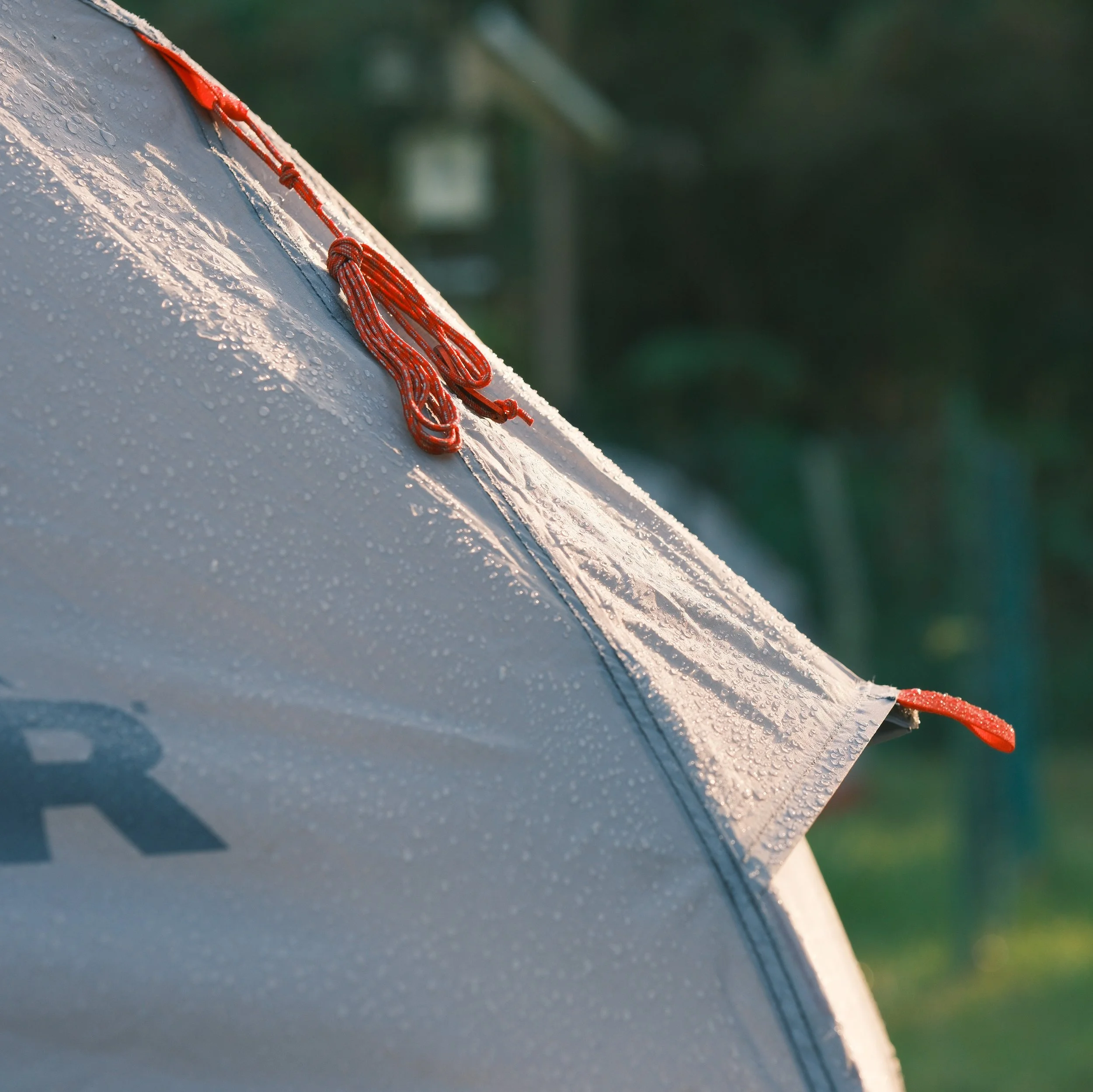 Parte de una tienda de campaña con cuerda y gotas de agua en la superficie.