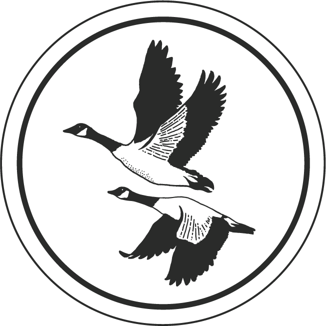 Silhouette of two flying geese inside a circular border.