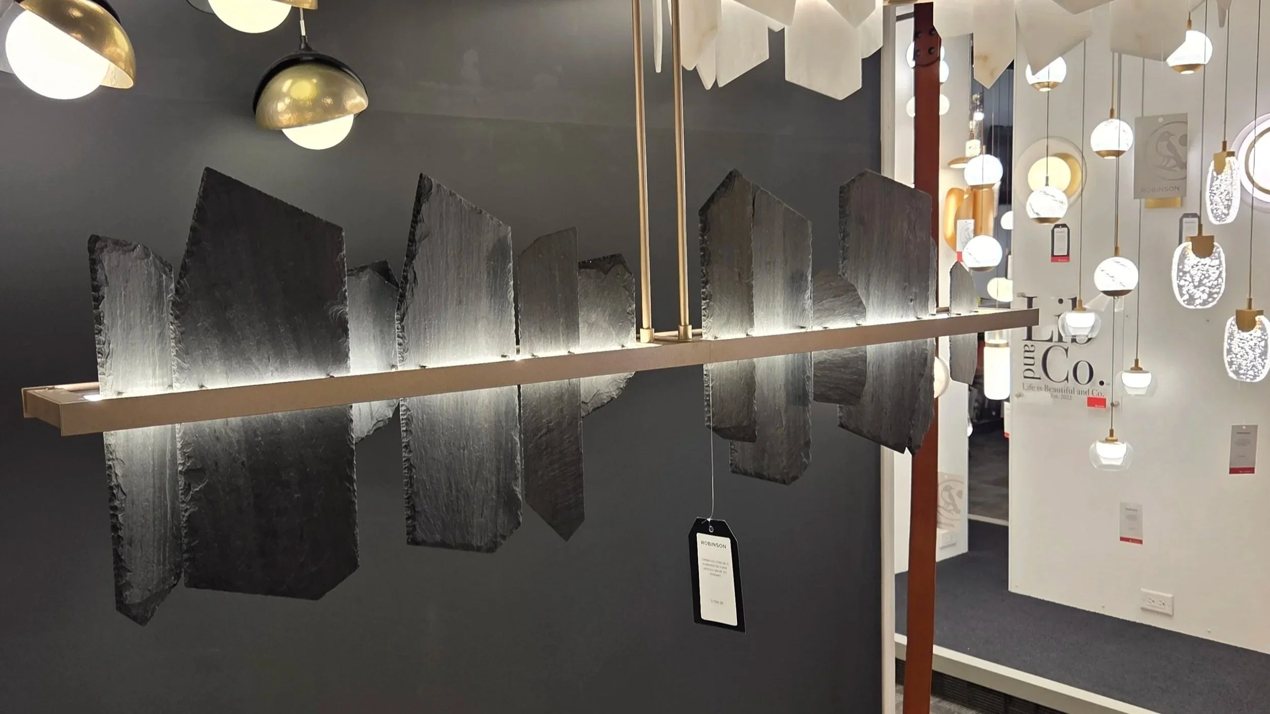 Display of modern hanging pendant lights in various shapes and colors in a lighting store.