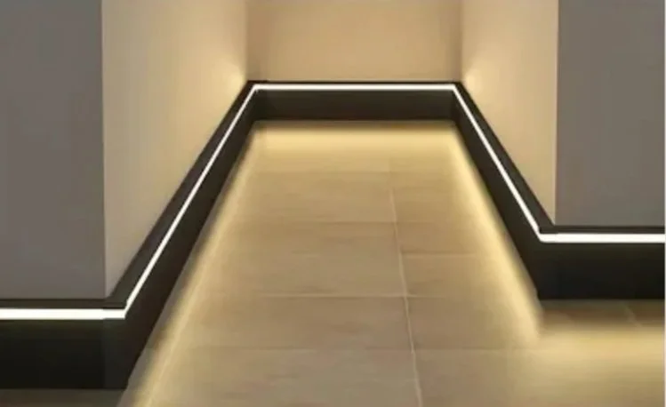 Close-up of a modern hallway with LED strip lighting along the baseboards and tiled flooring.