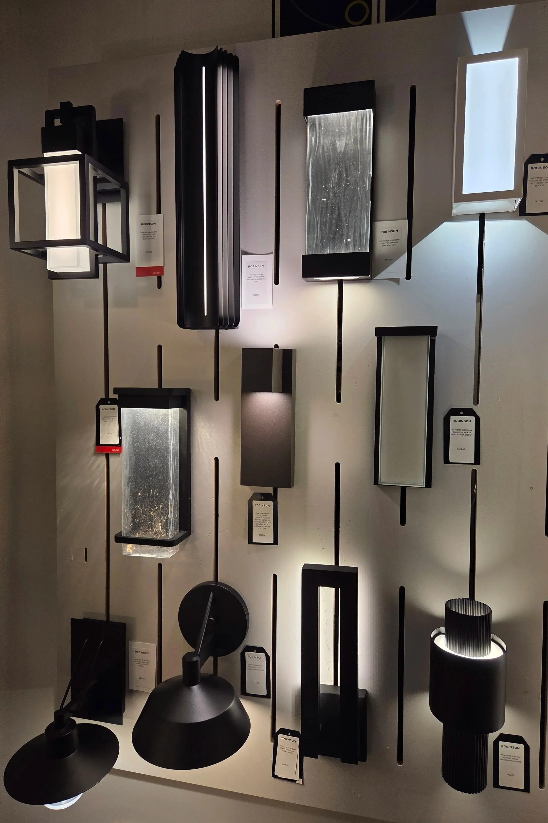 Display of modern pendant and table lamps in black and metallic finishes at a lighting store.