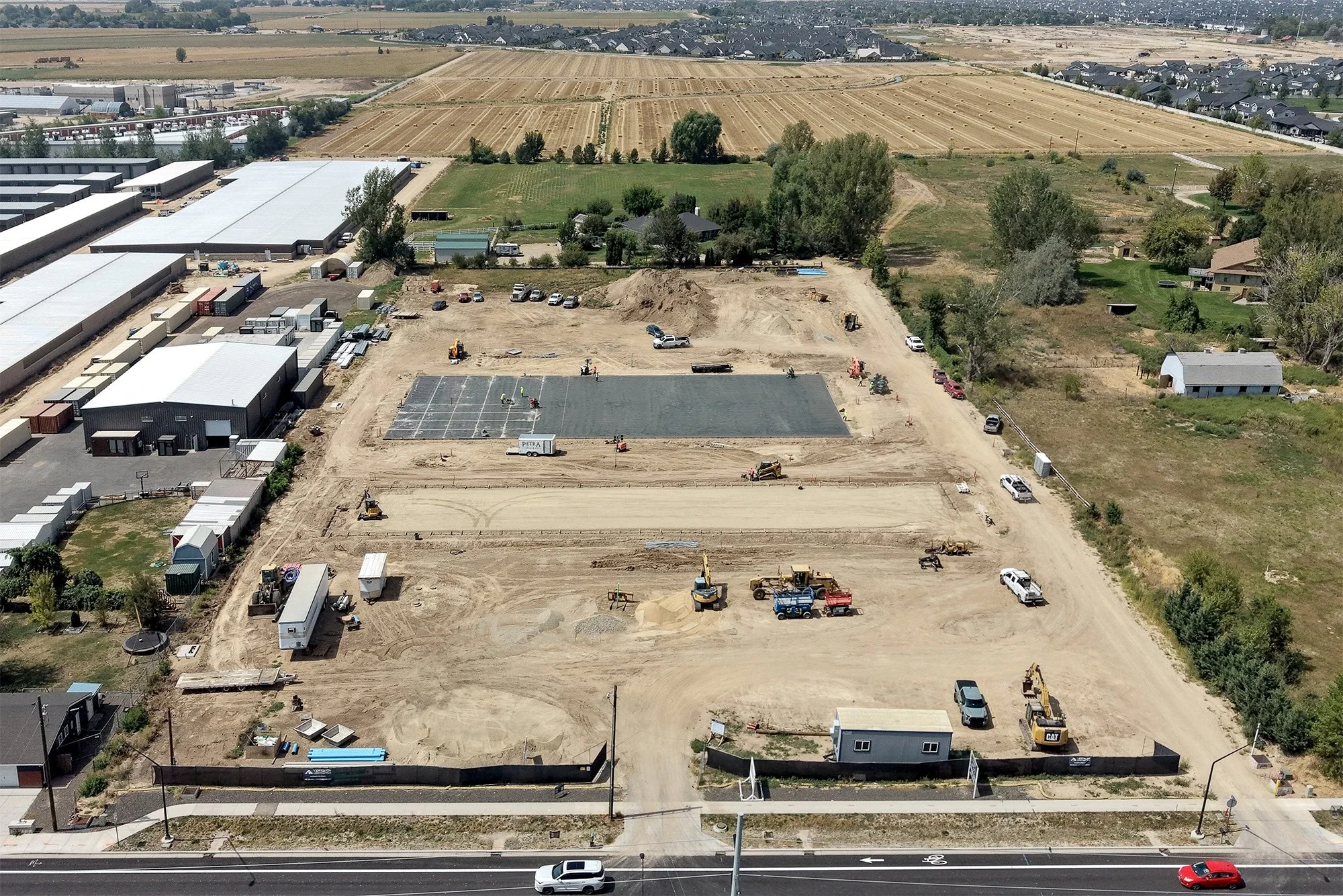Aerial drone photo of the Ten Mile Storage Condos construction site in August 2026 showing graded pads, excavators, footings and the site fronting N Ten Mile Road with the North Meridian growth corridor beyond