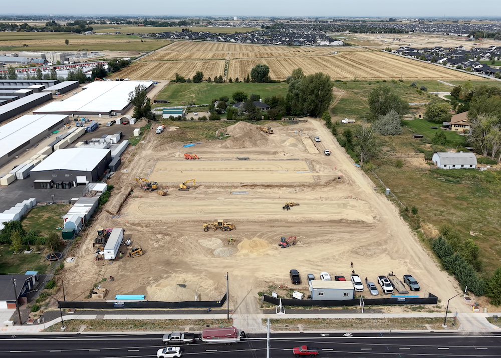 Aerial drone photo of the Ten Mile Storage Condos construction site in August 2026 showing graded pads, excavators, footings and the site fronting N Ten Mile Road with the North Meridian growth corridor beyond