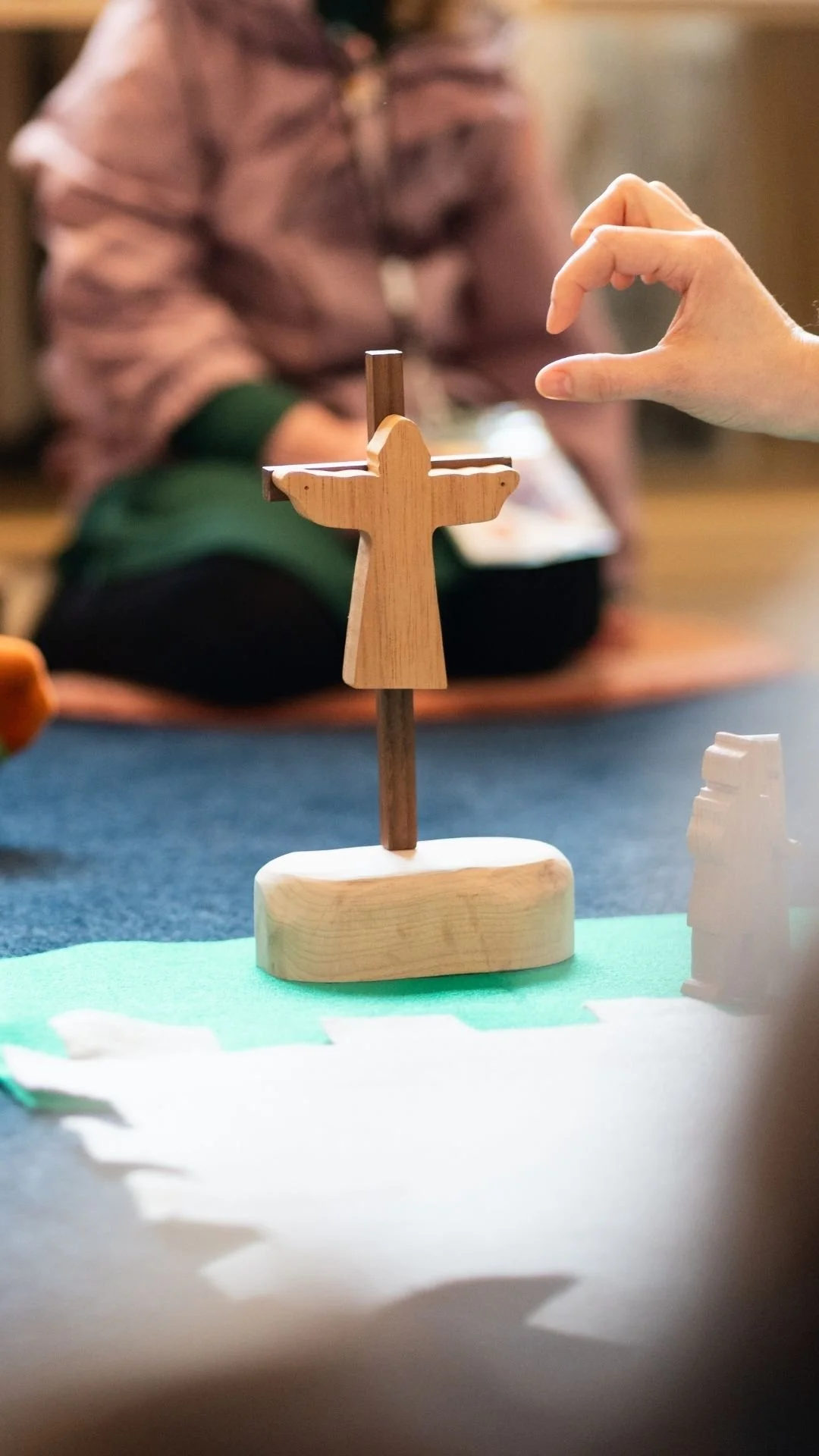hand reaching for a wooden figurine