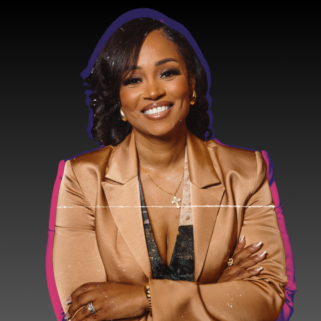 Veronica Thompson with dark hair styled in loose waves, wearing gold jewelry and a satin bronze blazer over a dark patterned top, posing with arms crossed against a black background.