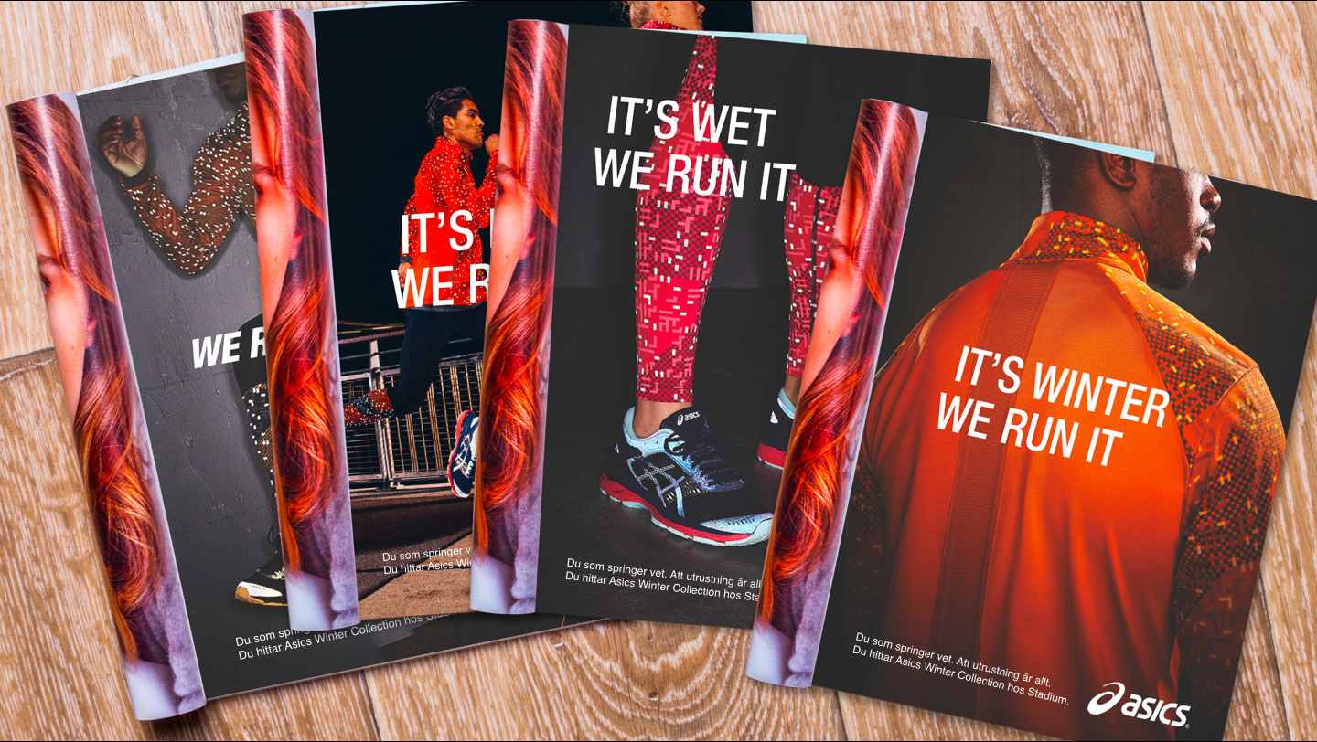 Promotional flyers for ASICS running shoes featuring diverse athletes, with bold text like 'IT'S WINTER WE RUN IT' and product images, laid out on a wooden surface.