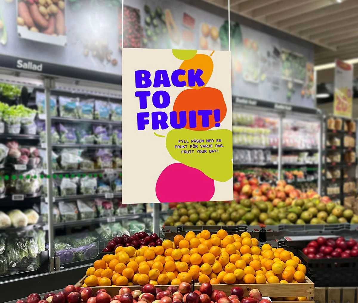 Sign that reads 'Back to Fruit!' with colorful fruit illustrations, in a grocery store produce section with baskets of oranges and apples.