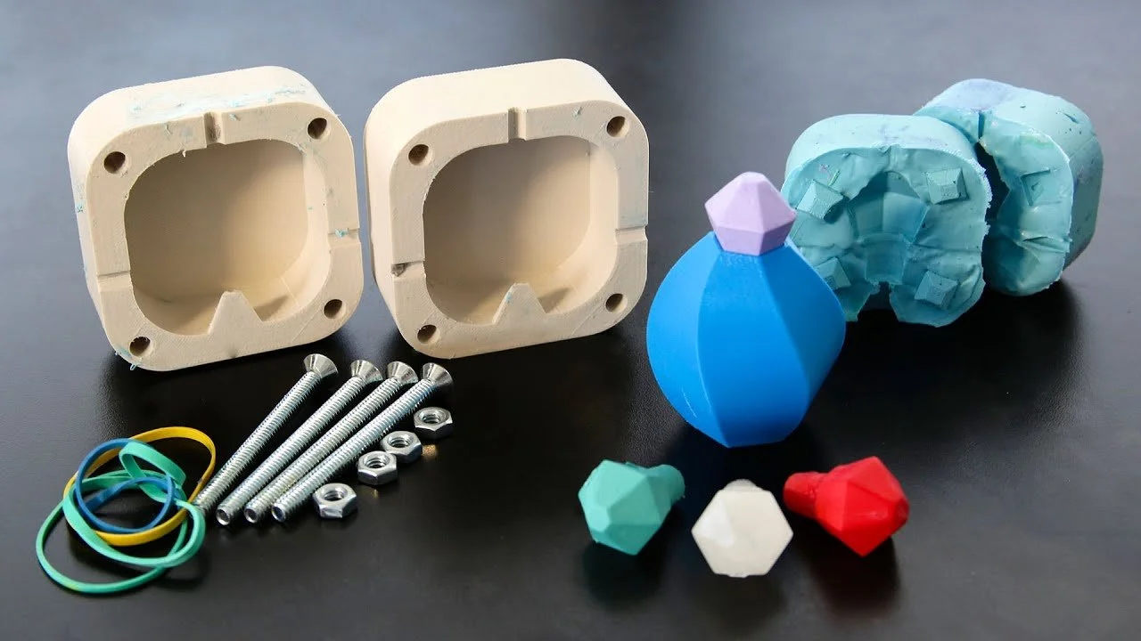 Plastic molds, screws, nuts, colorful rubber bands, and geometric toy pieces on a black surface.