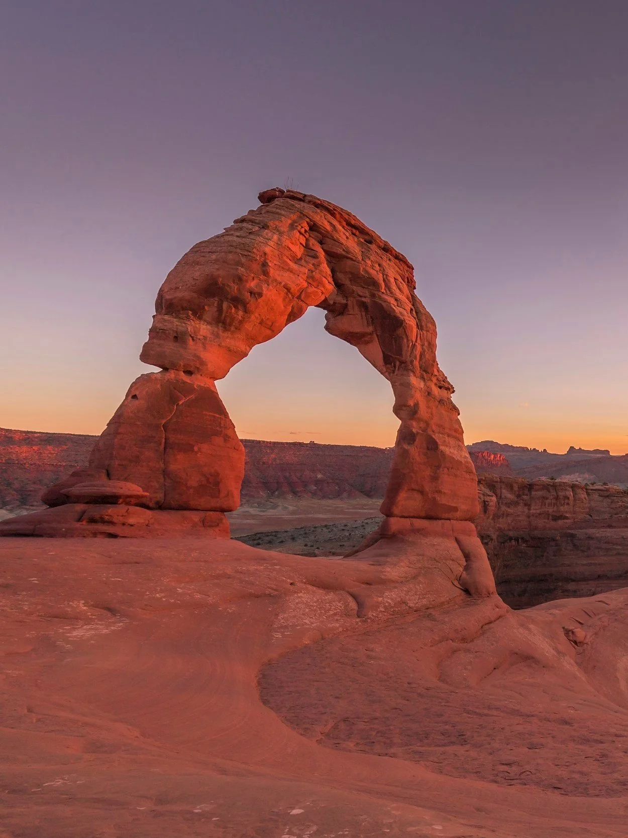 The Delicate Arch, a natural sandstone formation in Arches National Park, Utah, during sunset with a colorful sky.