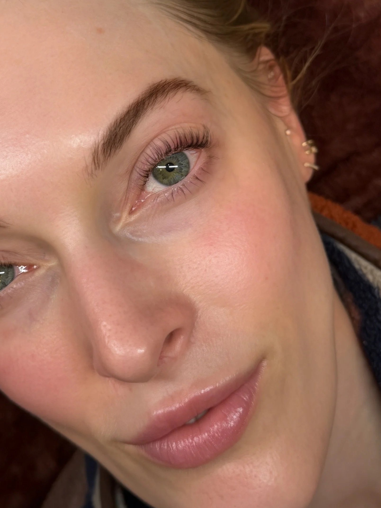 Close-up of a person's eye with long eyelashes, blue iris, and well-groomed eyebrow.
