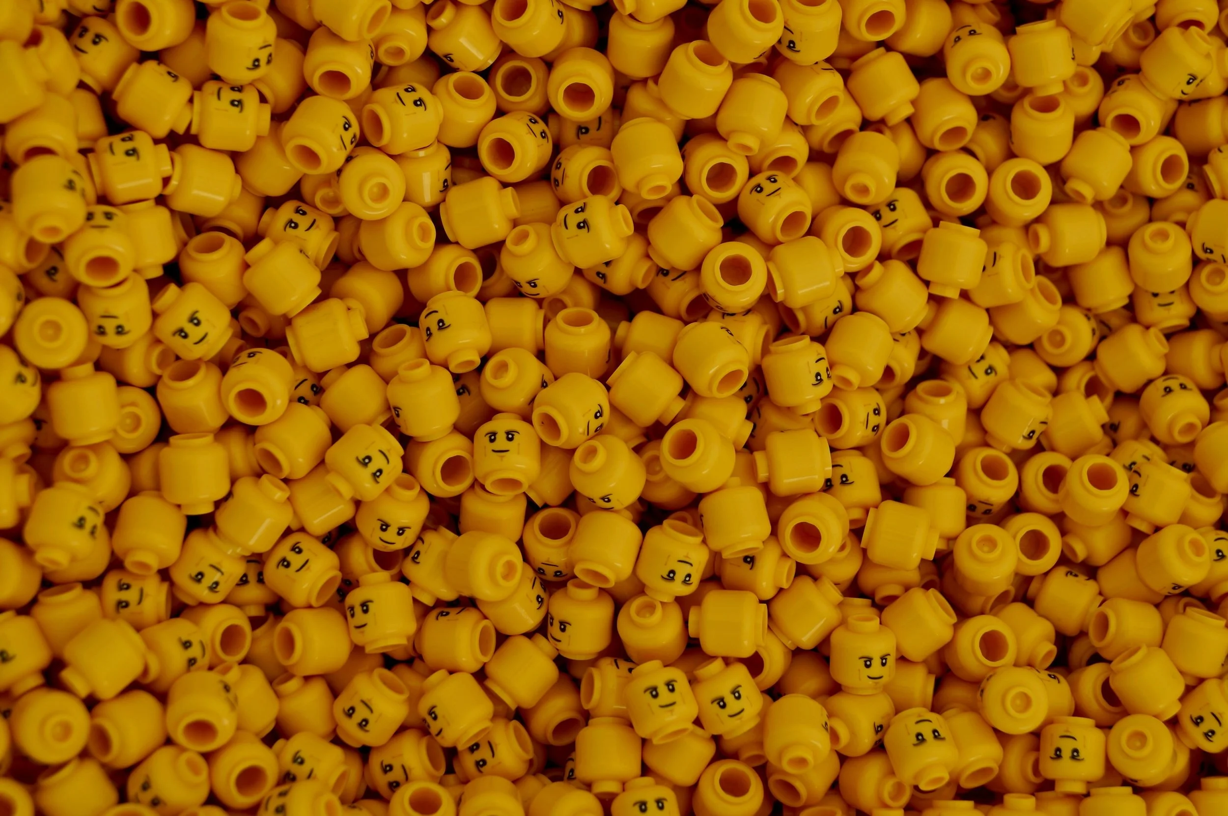 close-up photo of a bunch of lego heads in yellow-orange, photo by James Orr on unsplash