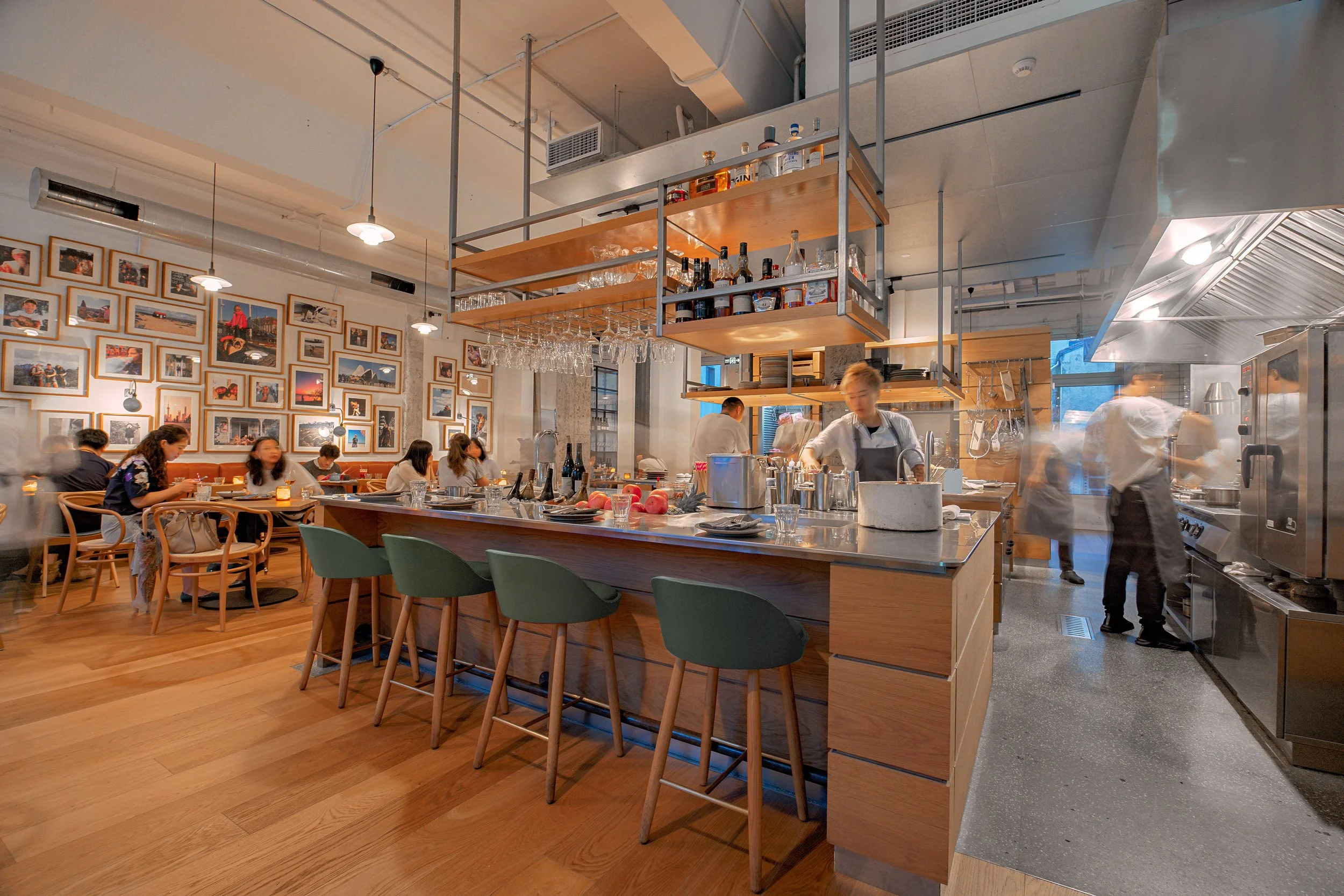 Chef preparing dishes at BOR Eatery's open kitchen, engaging with guests in a warmly lit dining space