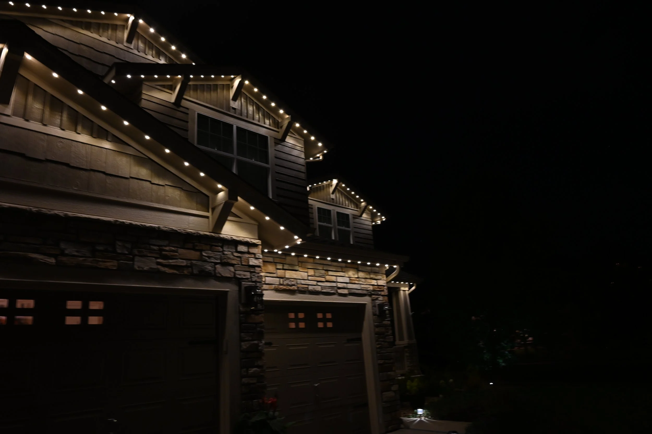 Nighttime view of a house decorated with Shine Lighting's lights along roof edges and window trims.